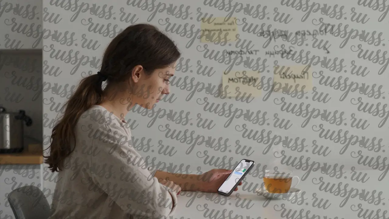 Женщина за кухонным столом, на телефоне сообщение 'Всё в порядке', на стене — напоминания о безопасности.